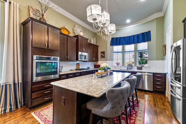 kitchen with stainless steel appliances, a kitchen island, pendant lighting, and dark brown cabinetry