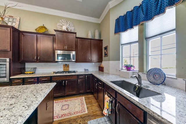 kitchen featuring sink, stainless steel appliances, light stone counters, and crown molding