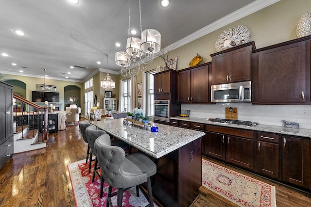 kitchen featuring a center island, appliances with stainless steel finishes, a kitchen bar, and hanging light fixtures