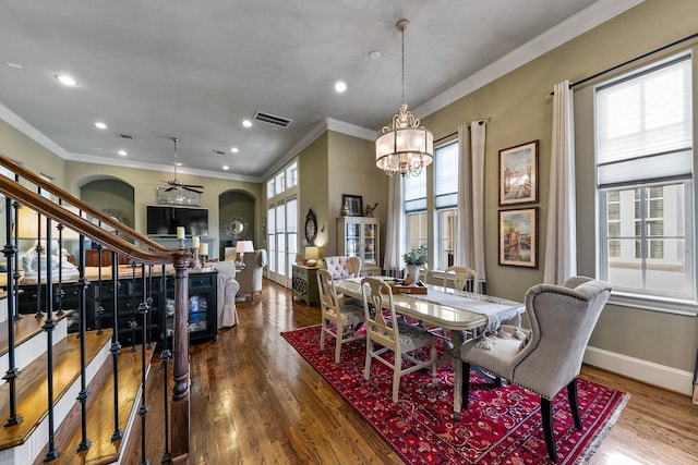 dining area with ceiling fan with notable chandelier, wood-type flooring, and crown molding