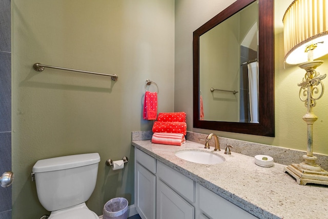 bathroom with toilet, walk in shower, and vanity