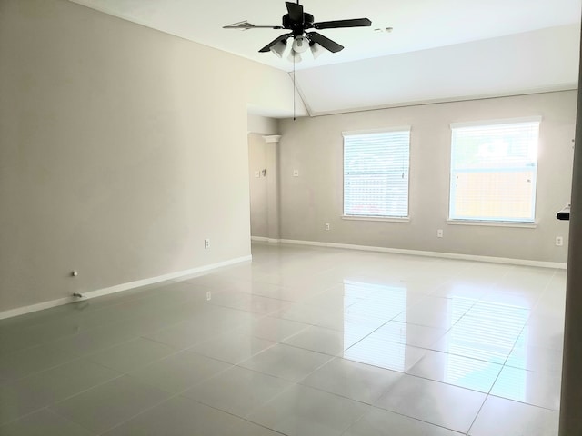 spare room featuring ceiling fan, light tile patterned flooring, and vaulted ceiling