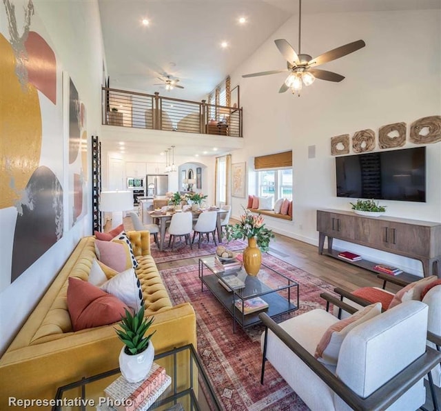 living room featuring hardwood / wood-style flooring, high vaulted ceiling, and ceiling fan