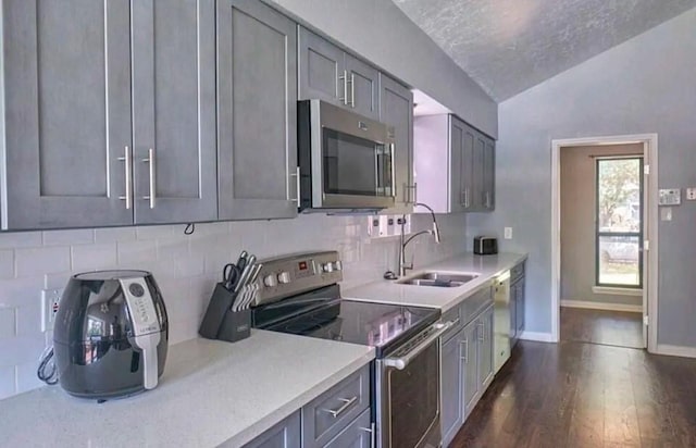 kitchen with sink, vaulted ceiling, decorative backsplash, a textured ceiling, and stainless steel appliances