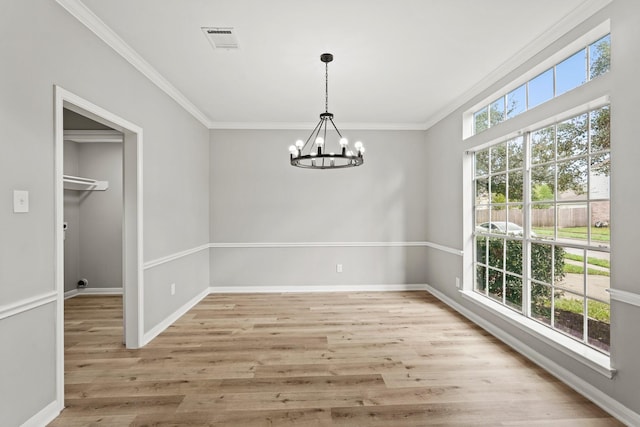 unfurnished dining area featuring ornamental molding, light wood-type flooring, and a notable chandelier