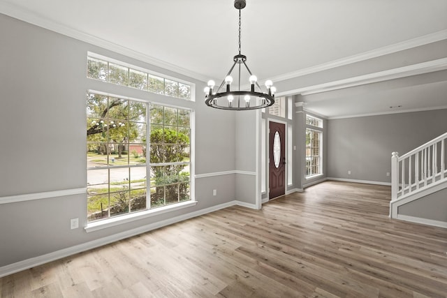 entryway featuring hardwood / wood-style flooring, ornamental molding, and a notable chandelier