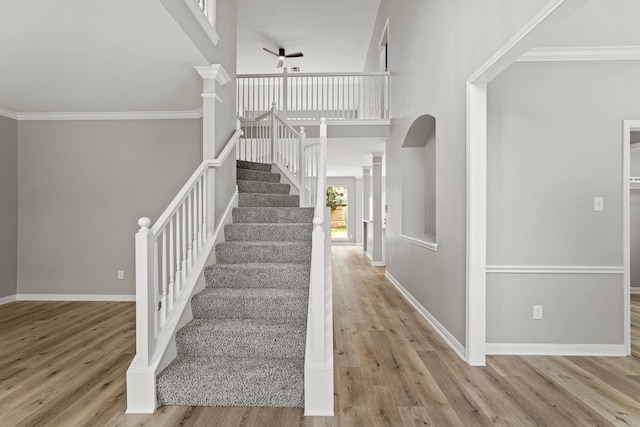 staircase with hardwood / wood-style flooring, ceiling fan, ornamental molding, and decorative columns