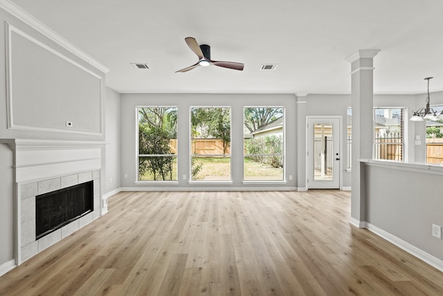 unfurnished living room with a fireplace, ceiling fan with notable chandelier, plenty of natural light, and light wood-type flooring