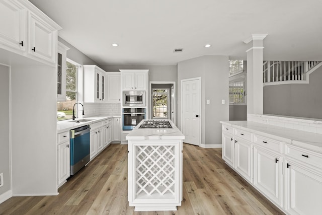 kitchen featuring ornate columns, white cabinetry, sink, a kitchen island, and appliances with stainless steel finishes