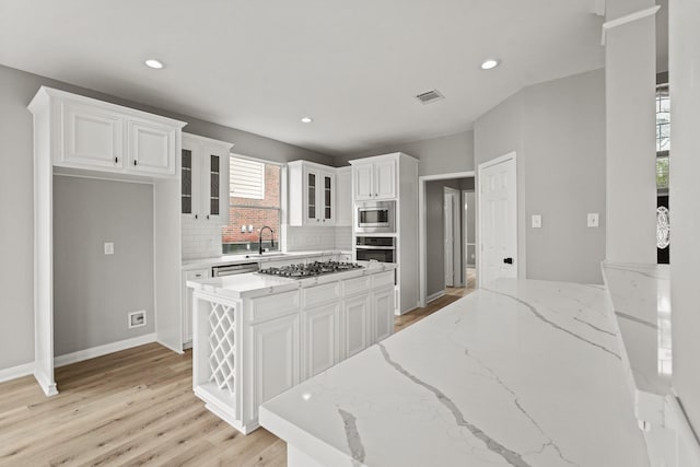 kitchen with sink, light stone countertops, a kitchen island, white cabinetry, and stainless steel appliances