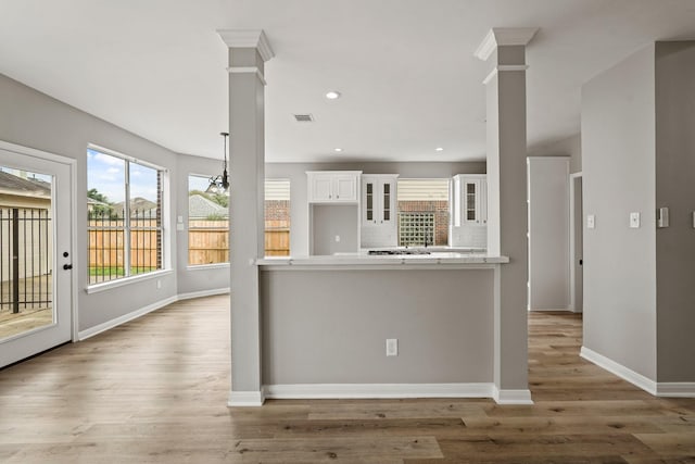 kitchen with white cabinets, tasteful backsplash, kitchen peninsula, and hardwood / wood-style flooring