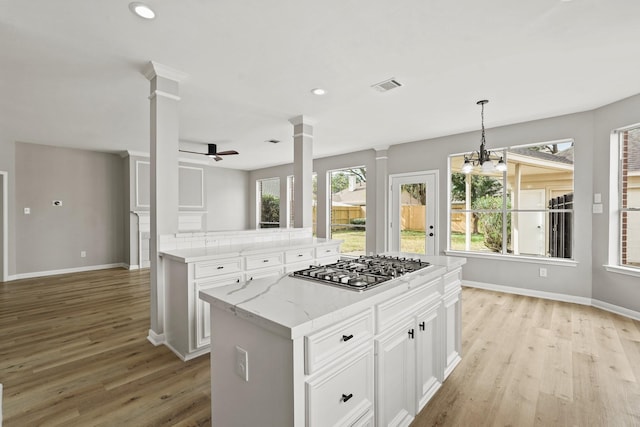 kitchen with white cabinetry, pendant lighting, ceiling fan with notable chandelier, and stainless steel gas stovetop