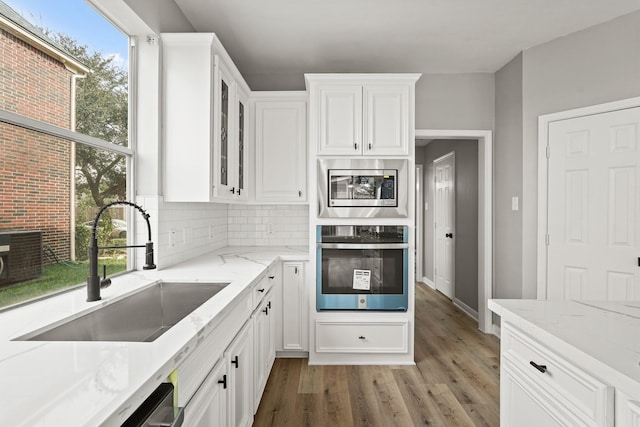 kitchen with white cabinetry, sink, stainless steel appliances, and light stone counters