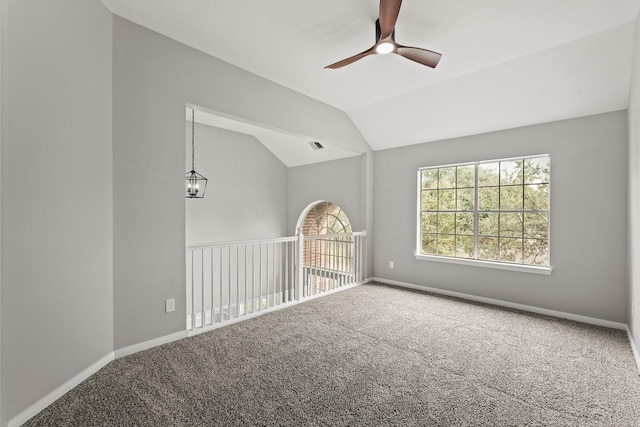 carpeted spare room featuring ceiling fan with notable chandelier and lofted ceiling