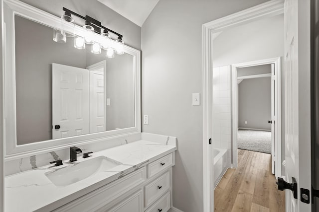 bathroom featuring hardwood / wood-style floors, vanity, shower / bath combination, and vaulted ceiling