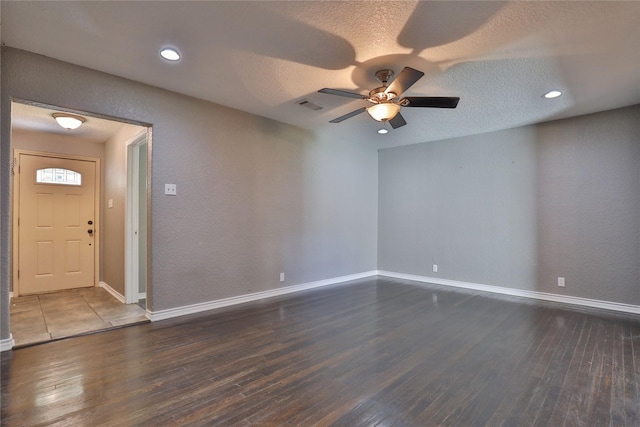 empty room featuring a textured ceiling, ceiling fan, and dark wood-type flooring