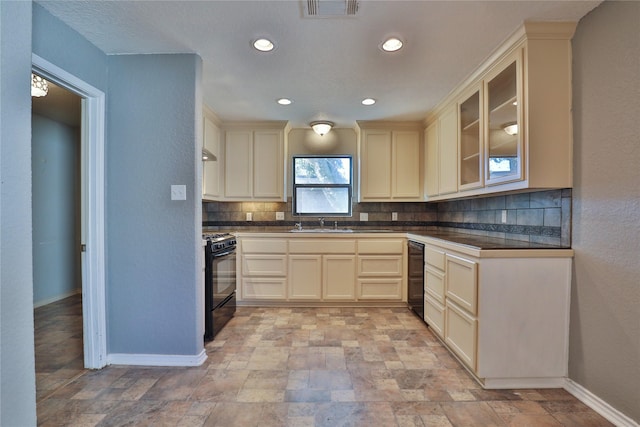 kitchen with decorative backsplash, sink, black range, and cream cabinetry