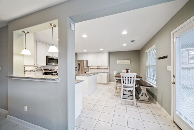 kitchen featuring white cabinets, kitchen peninsula, appliances with stainless steel finishes, and tasteful backsplash