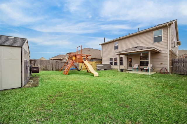 rear view of house featuring a playground, a yard, a patio, and a storage unit