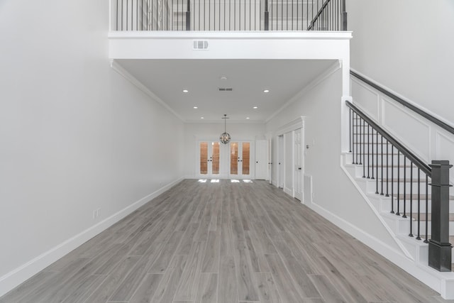 interior space with light hardwood / wood-style floors, crown molding, and french doors