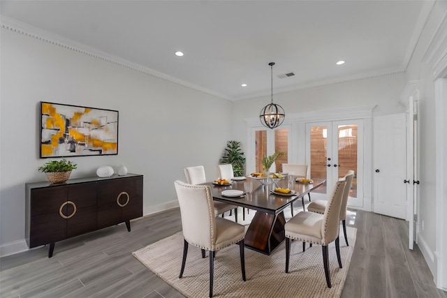 dining area featuring light hardwood / wood-style floors, crown molding, and a chandelier