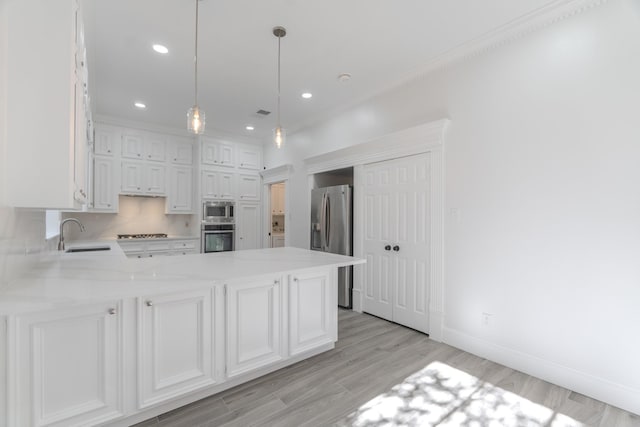 kitchen featuring kitchen peninsula, appliances with stainless steel finishes, decorative light fixtures, and sink