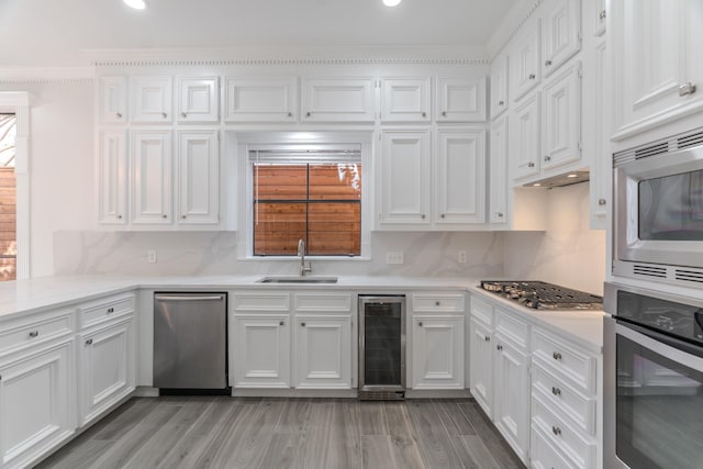 kitchen featuring sink, white cabinetry, stainless steel appliances, and wine cooler