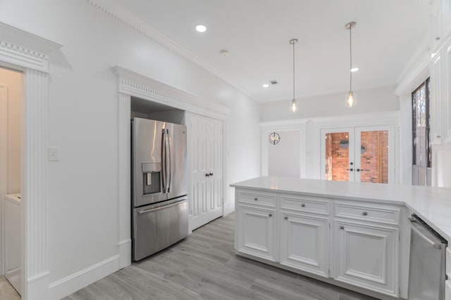 kitchen with light wood-type flooring, stainless steel appliances, crown molding, pendant lighting, and white cabinetry