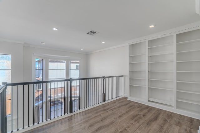 unfurnished room with built in shelves, a wealth of natural light, and hardwood / wood-style floors