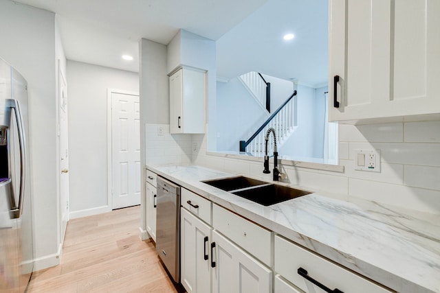 kitchen with decorative backsplash, stainless steel appliances, sink, light hardwood / wood-style flooring, and white cabinets