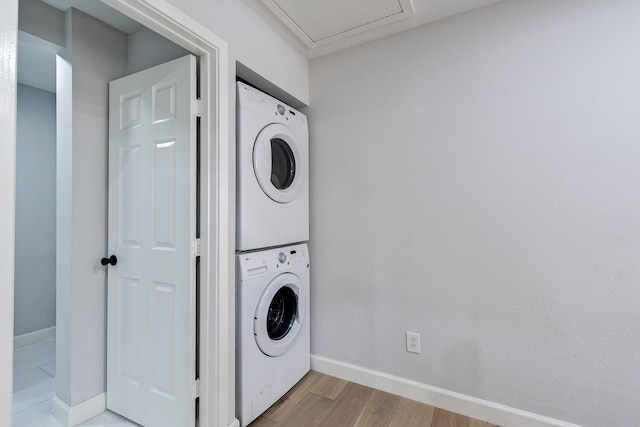 washroom with light wood-type flooring and stacked washer / dryer