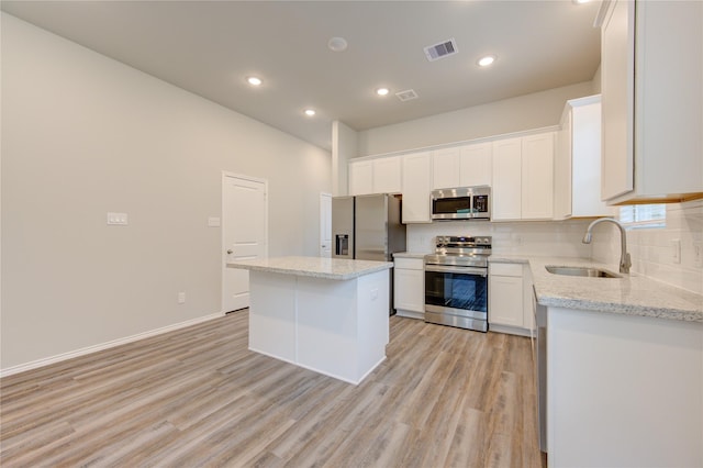 kitchen with white cabinetry, sink, stainless steel appliances, backsplash, and a kitchen island