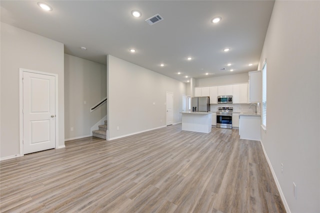 unfurnished living room featuring light hardwood / wood-style floors and sink