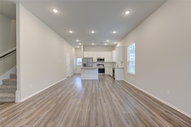 unfurnished living room featuring a healthy amount of sunlight, sink, and light hardwood / wood-style flooring