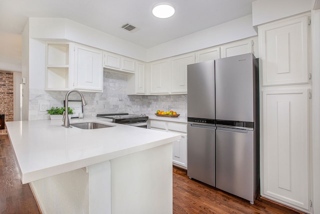 kitchen with white cabinets, appliances with stainless steel finishes, decorative backsplash, sink, and kitchen peninsula