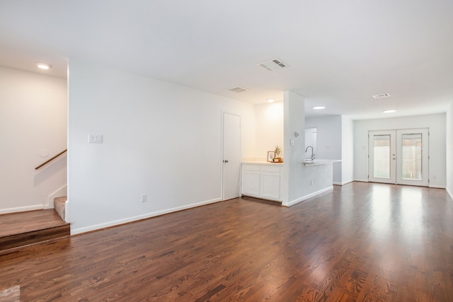 unfurnished living room featuring sink, french doors, and dark hardwood / wood-style flooring