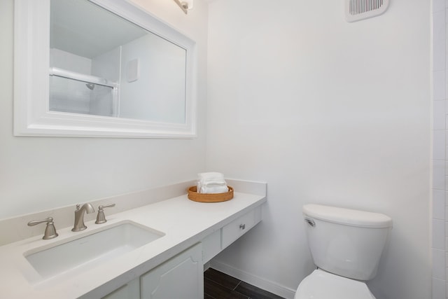 bathroom featuring vanity, toilet, and a shower with shower door