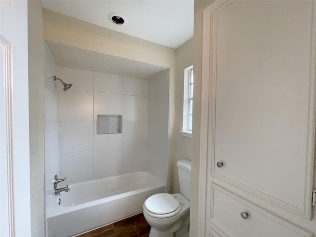 bathroom with wood-type flooring, toilet, and tiled shower / bath