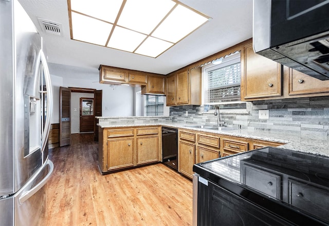 kitchen with backsplash, light hardwood / wood-style floors, black appliances, kitchen peninsula, and sink