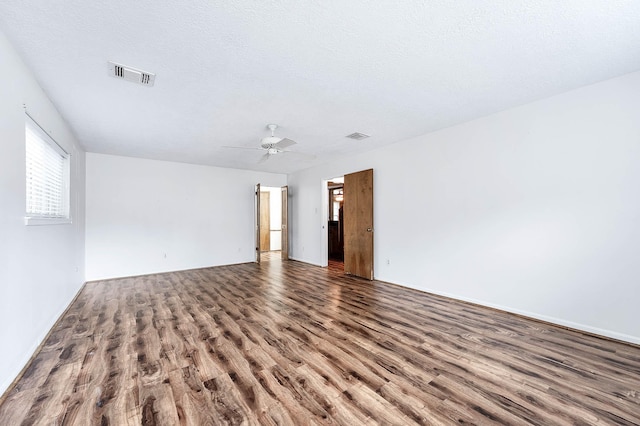 unfurnished room featuring ceiling fan, dark wood-type flooring, a textured ceiling, and a wealth of natural light