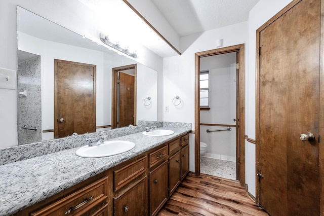 bathroom with toilet, a textured ceiling, wood-type flooring, and vanity