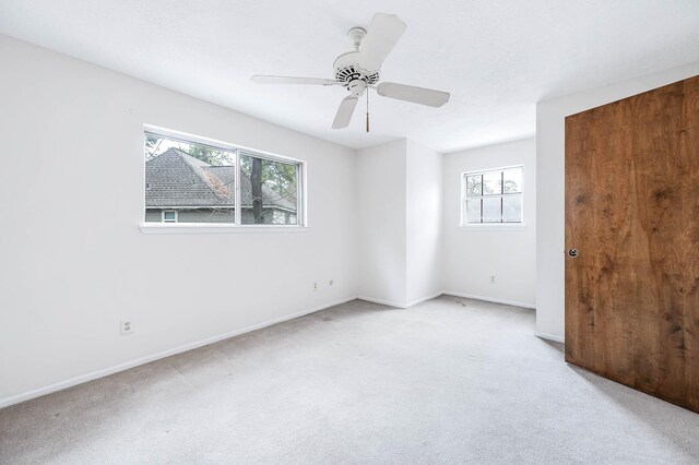 carpeted spare room featuring ceiling fan and a wealth of natural light