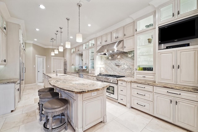 kitchen with decorative light fixtures, tasteful backsplash, a breakfast bar area, a kitchen island with sink, and light stone counters