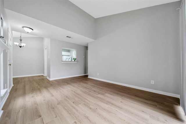 unfurnished room with light hardwood / wood-style floors and an inviting chandelier