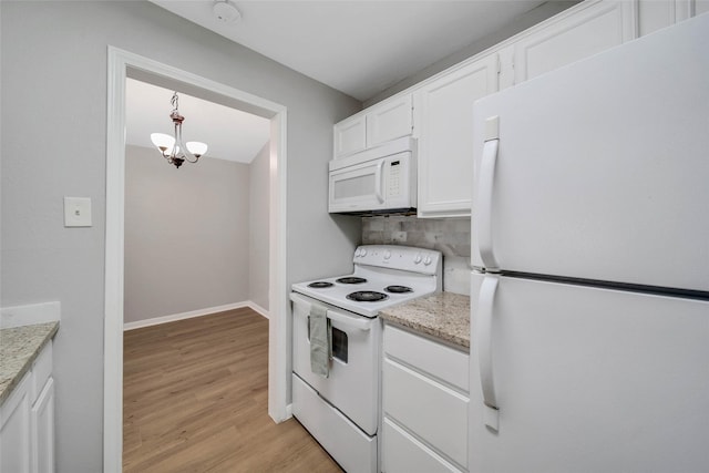 kitchen featuring white cabinets, light stone counters, white appliances, and hanging light fixtures