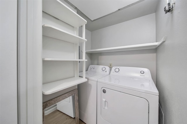 laundry room with washing machine and dryer and light hardwood / wood-style flooring