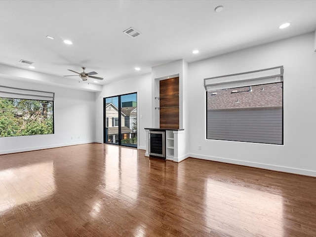 unfurnished living room featuring ceiling fan, beverage cooler, and wood-type flooring