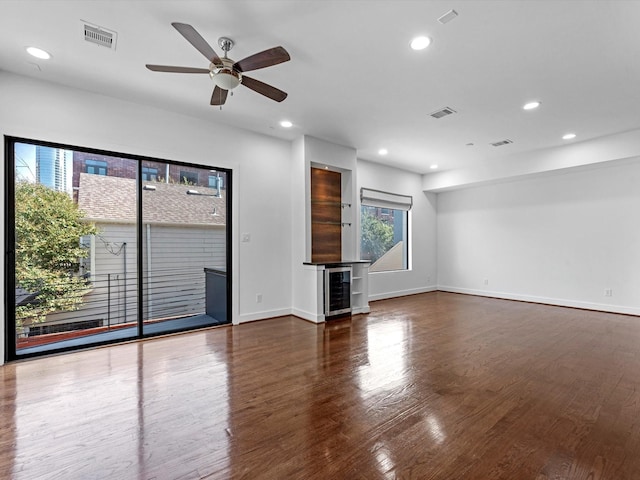 unfurnished living room with ceiling fan, beverage cooler, and dark wood-type flooring