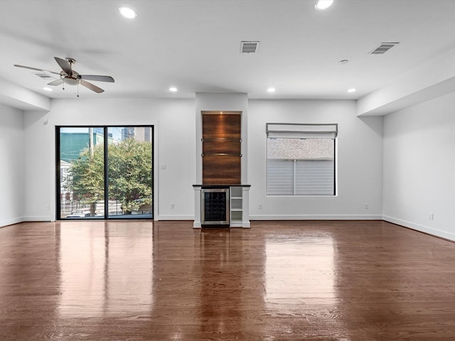 unfurnished living room with wine cooler, ceiling fan, and dark hardwood / wood-style flooring