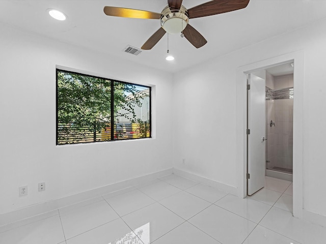 unfurnished bedroom featuring ensuite bath, ceiling fan, light tile patterned flooring, and a spacious closet